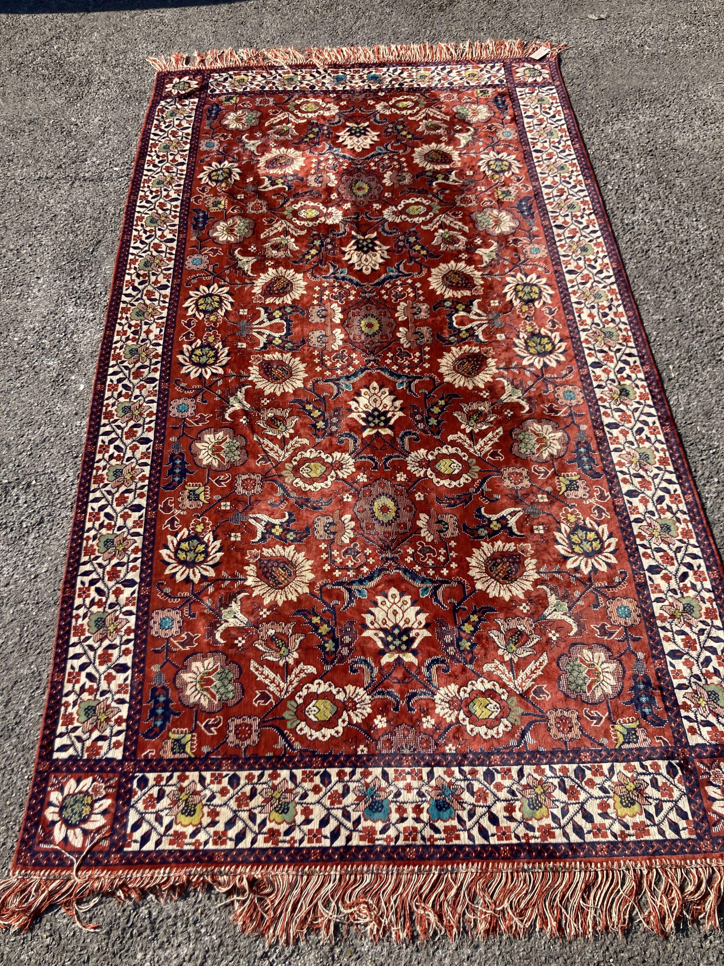 A large embroidered silk rug with a claret red ground interspersed with symmetrical foliate decoration, 136 x 260cm